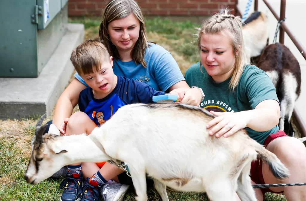 Boy petting a goat at No Limits Summer Camp