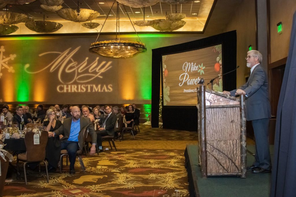 Christmas extravaganza with speakers podium, video screen and guests seated at dinner tables